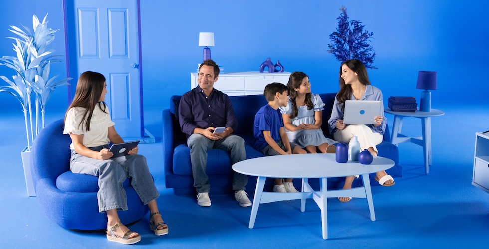 A happy family wearing various shades of blue sits in a room styled with blue furniture and decor.
